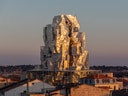 Gebäude mit unregelmässiger, glänzender Fassade im Sonnenuntergang.