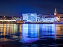 Beleuchtete Gebäude am Flussufer bei Nacht.