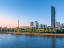 Stadtansicht mit Fluss und modernen Hochhäusern bei Sonnenuntergang.