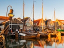 Historischer Hafen mit Segelbooten und Häusern im Abendlicht.