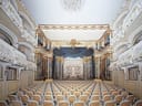 Prunkvolles Theaterinterieur mit leeren Sitzreihen und dekorierter Bühne.