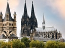 Historische Kathedrale und Kirche mit Türmen und Bäumen im Vordergrund.
