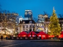Weihnachtsmarkt mit Lichtern und geschmücktem Baum bei Abenddämmerung.