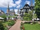 Historisches Gebäude mit Garten und Türmen unter blauem Himmel.