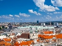 Stadtansicht mit roten Dächern und blauem Himmel.