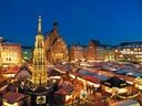 Weihnachtsmarkt mit beleuchteten Ständen und Kirche im Hintergrund.
