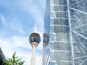 Fernsehturm hinter Glasgebäude mit blauem Himmel.