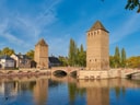 Zwei historische Türme und Steinbrücke über Fluss in Strassburg.