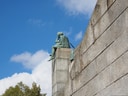 Statue auf einer Mauer vor blauem Himmel.