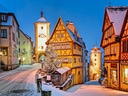 Verschneite Altstadt mit Fachwerkhäusern und Turm am Abend.