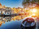 Amsterdamer Kanalhäuser bei Sonnenuntergang, Boote am Wasser.