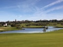 Landschaft mit Golfplatz und kleinem See.