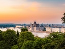Panorama einer Stadt mit Fluss, Brücke und grossem Gebäude im Sonnenuntergang.