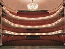 Innenansicht eines leeren Theaters mit Balkonen und Kronleuchter.