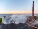 Altes Industriegebäude mit Dampfwolken bei Sonnenuntergang.