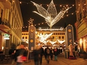 Weihnachtsmarkt mit Lichterketten und Menschenmenge am Abend.