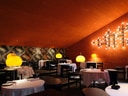 Elegantes Restaurant mit runden Tischen und orange Beleuchtung.