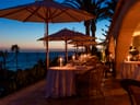 Terrasse eines Restaurants bei Sonnenuntergang mit Kerzenbeleuchtung und Meerblick.
