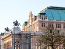 Historisches Gebäude mit Skulpturen auf dem Dach bei Sonnenuntergang.