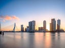 Skyline von Rotterdam im Sonnenuntergang mit Brücke und modernen Gebäuden.
