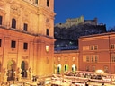 Weihnachtsmarkt vor beleuchteter barocker Kirche in Salzburg.