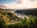 Blick auf Flusstal mit Weinbergen und Burg im Hintergrund.