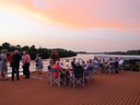 Menschen auf dem Deck eines Kreuzfahrtschiffs bei Sonnenuntergang.