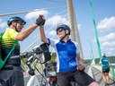 Zwei Radfahrer schlagen auf einer Brücke ein.