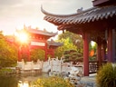 Traditioneller chinesischer Garten mit Pavillon und Brücke im Sonnenuntergang.