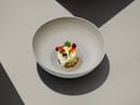 Elegantes Dessert in einer grauen Schüssel auf gemustertem Hintergrund.