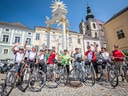 Gruppe von Radfahrern vor barockem Brunnen in Altstadt.