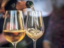 Weisswein wird in ein Glas gegossen.