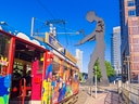 Bunte Strassenbahn und grosse Skulptur in der Stadt.