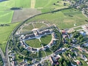 Luftaufnahme eines kreisförmigen Parks mit Gebäuden in ländlicher Umgebung.