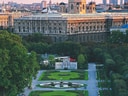 Historisches Gebäude mit gepflegten Gärten im Vordergrund bei Sonnenuntergang.