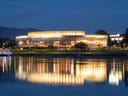 Beleuchtetes Gebäude am Abend mit Spiegelung im Wasser.