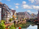 Malerische Altstadt mit Fachwerkhäusern und Kanal bei Sonnenschein.
