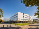 Moderne weisse Bürogebäude mit Bäumen im Vordergrund.