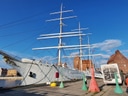 Historisches Segelschiff im Hafen mit Infotafeln im Vordergrund.