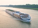 Flusskreuzfahrtschiff auf einem breiten Fluss.