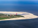 Luftaufnahme von Sanddüne mit Leuchtturm an der Küste.