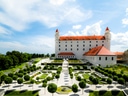 Schloss mit gepflegtem Garten unter blauem Himmel.
