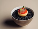 Kleine Schüssel mit schwarzen Bohnen, garniert mit einem kunstvollen Dessert.