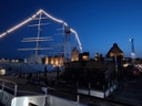 Beleuchtetes Segelschiff im nächtlichen Hafen.