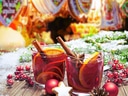 Zwei Glühweintassen mit Zimtstangen und Orangen.