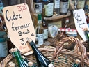 Korb mit Flaschen und Preisschildern auf einem Marktstand.