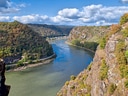 Blick auf eine Flussbiegung zwischen bewaldeten Hügeln.