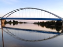 Brücke, die über einen ruhigen Fluss bei Sonnenuntergang verläuft.