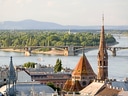 Blick auf Fluss, Brücken und Gebäude mit Kirchturm in Budapest.