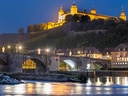 Beleuchtete Festung und historische Brücke bei Nacht in Würzburg.